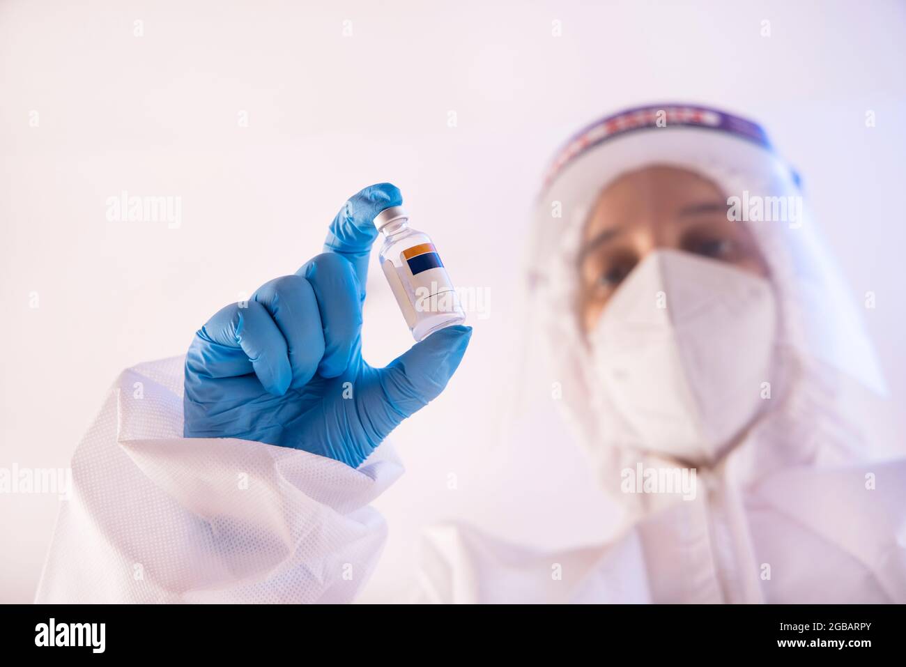 Un médecin dans la trousse d'EPI tenant en main une bouteille de vaccin contre le covid. Banque D'Images