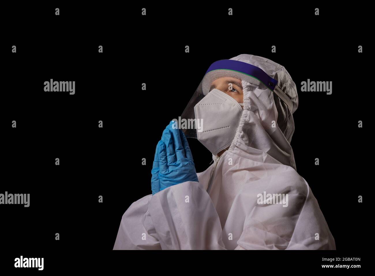 Un médecin en kit PPE se joint à la main dans la prière. Banque D'Images