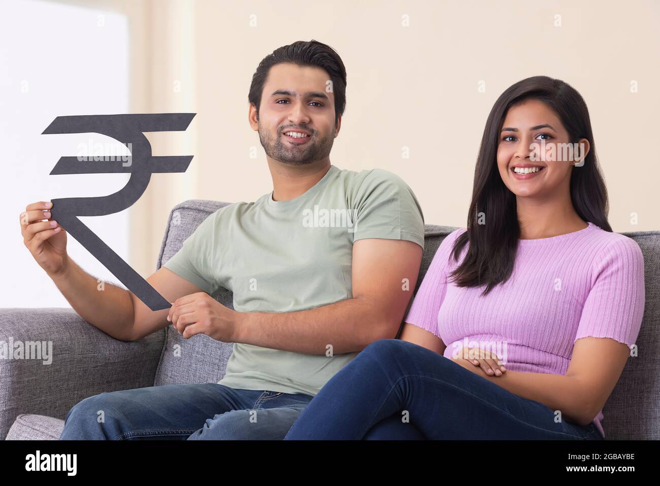 Une jeune femme assise avec un homme tenant le signe de la monnaie indienne à la main. Banque D'Images