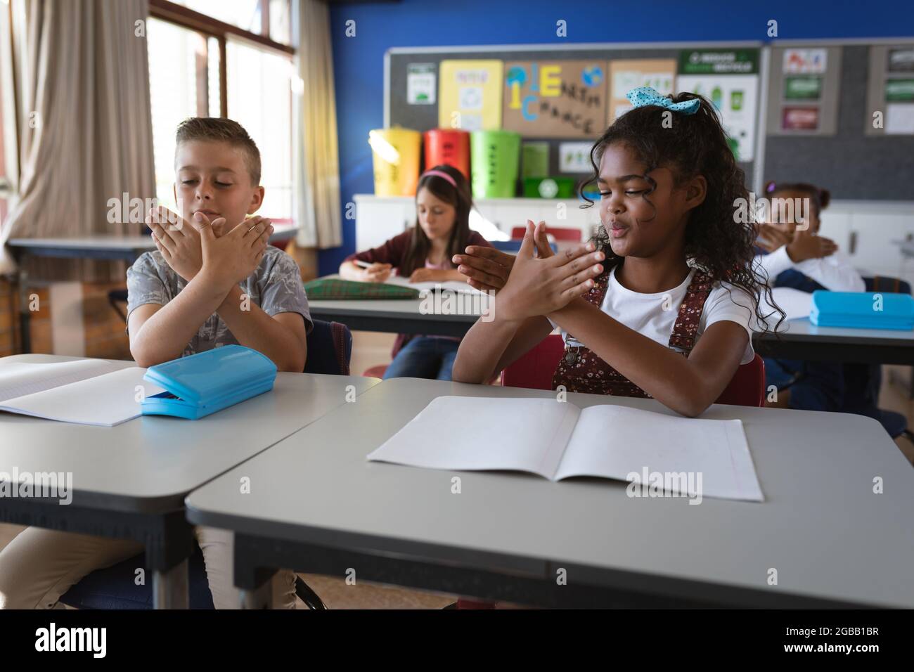 Une fille afro-américaine et un garçon caucasien parlent entre eux dans la langue des signes à l'école Banque D'Images