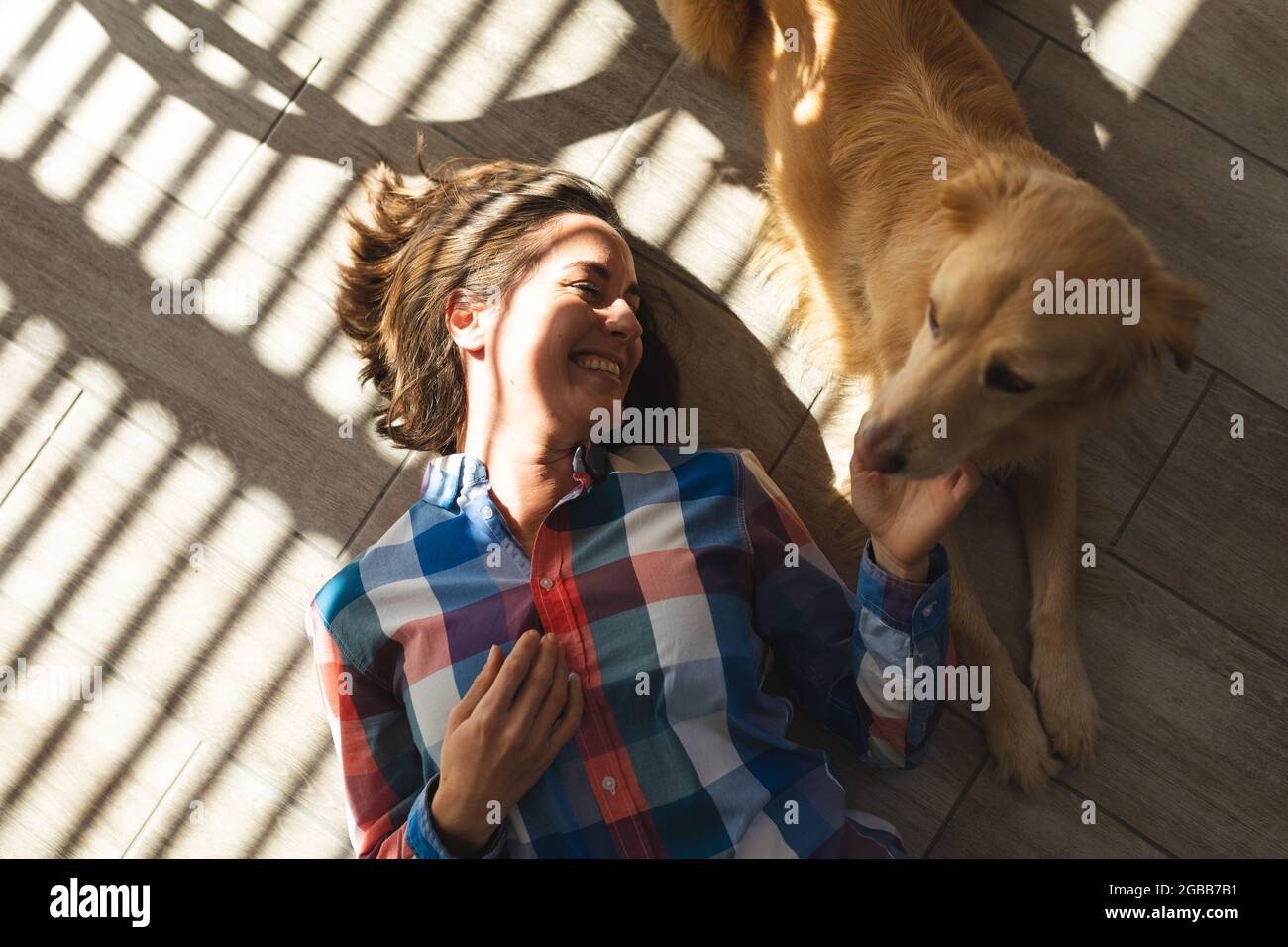 Femme caucasienne couchée sur le sol souriant et petant son chien Banque D'Images