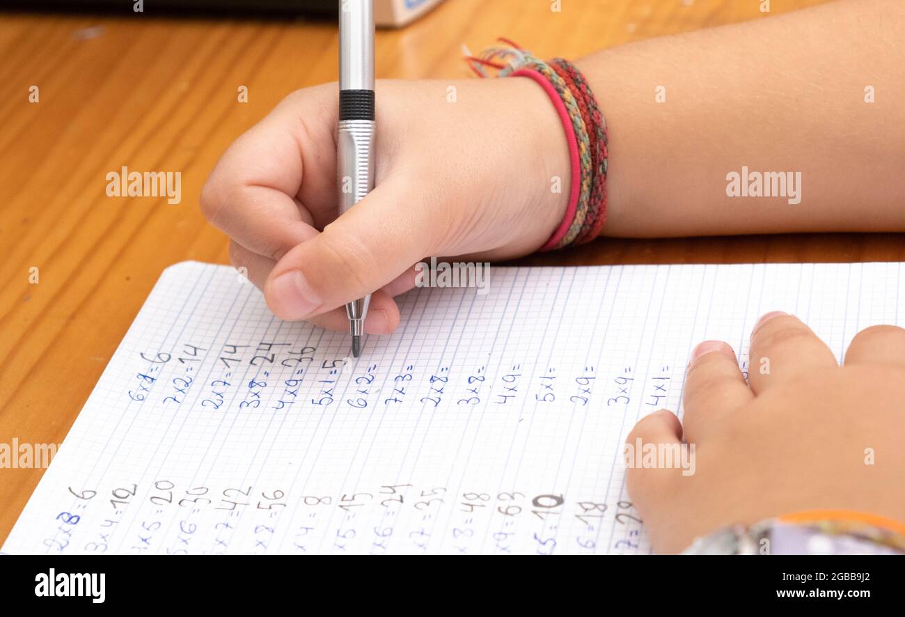 Photo de côté d'une petite fille écrivant les tables de multiplication. Concept de la rentrée, des devoirs, de l'apprentissage des mathématiques. Banque D'Images