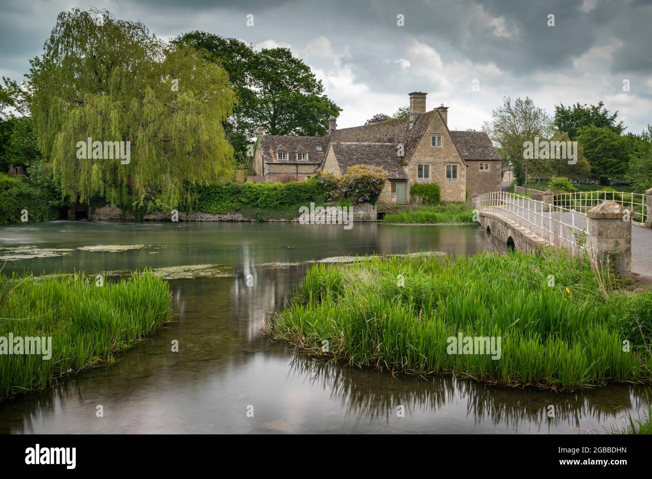 Jolie maison de moulin sur les rives de la rivière Coln au printemps dans le village des Cotswolds de Fairford, Gloucestershire, Angleterre, Royaume-Uni, Europe Banque D'Images