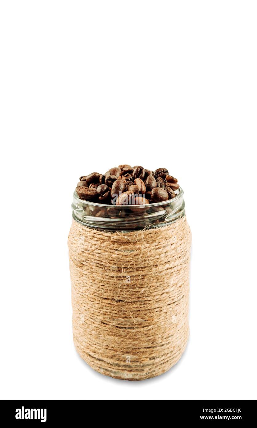 Grains de café torréfiés dans un pot en verre, grains de café entiers dans un pot brun. Isoler. Copier l'espace. Banque D'Images