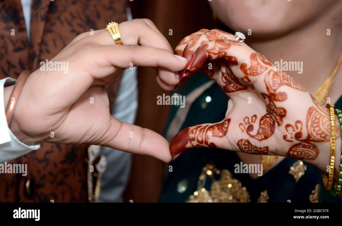 Gros plan de jeunes jeunes mariés faisant un geste de coeur avec leurs mains Banque D'Images