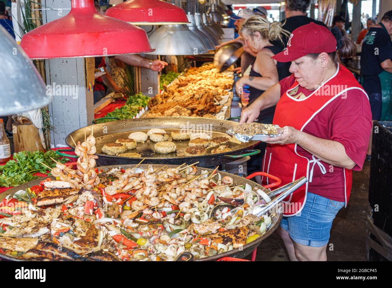 Everglades City Florida, Seafood Festival food, stand fournisseur crevettes crevettes crevettes paella crabe gâteaux, femme hispanique cuisinière femme cuisine préparation assiette dis Banque D'Images