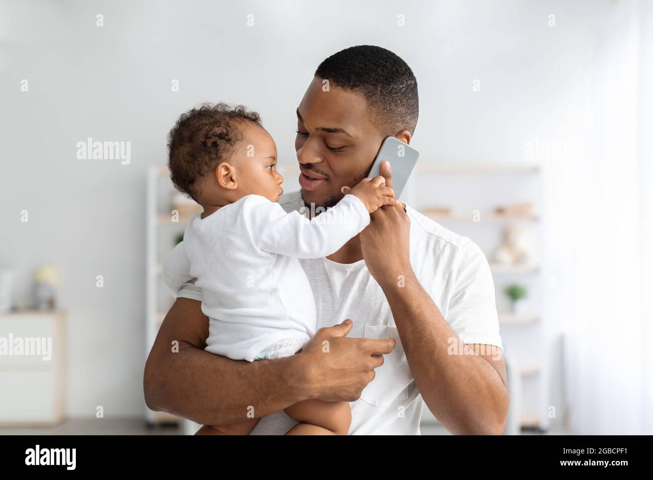 Adorable Petit Bebe Noir Jouant Avec Le Telephone Portable Pendant Que Le Pere Parle Dessus Photo Stock Alamy