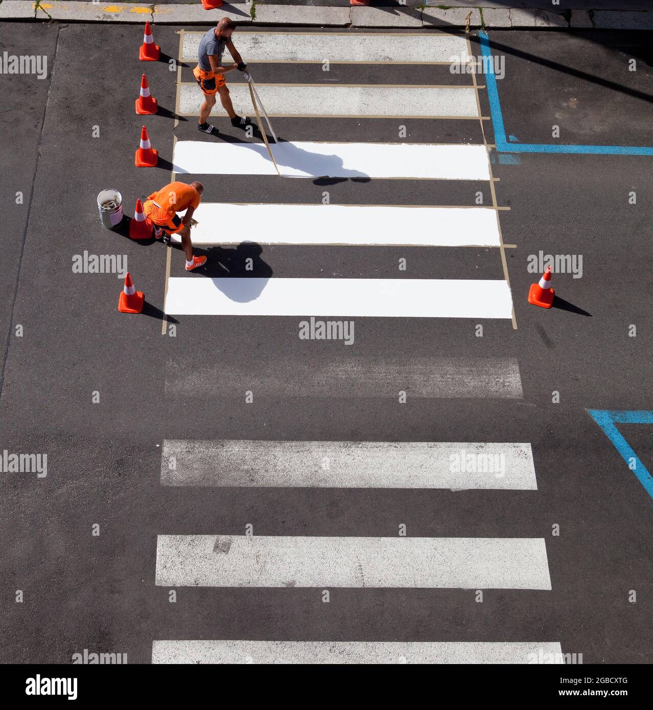 Les travailleurs peignant des bandes de traverse de couleur blanche. Banque D'Images
