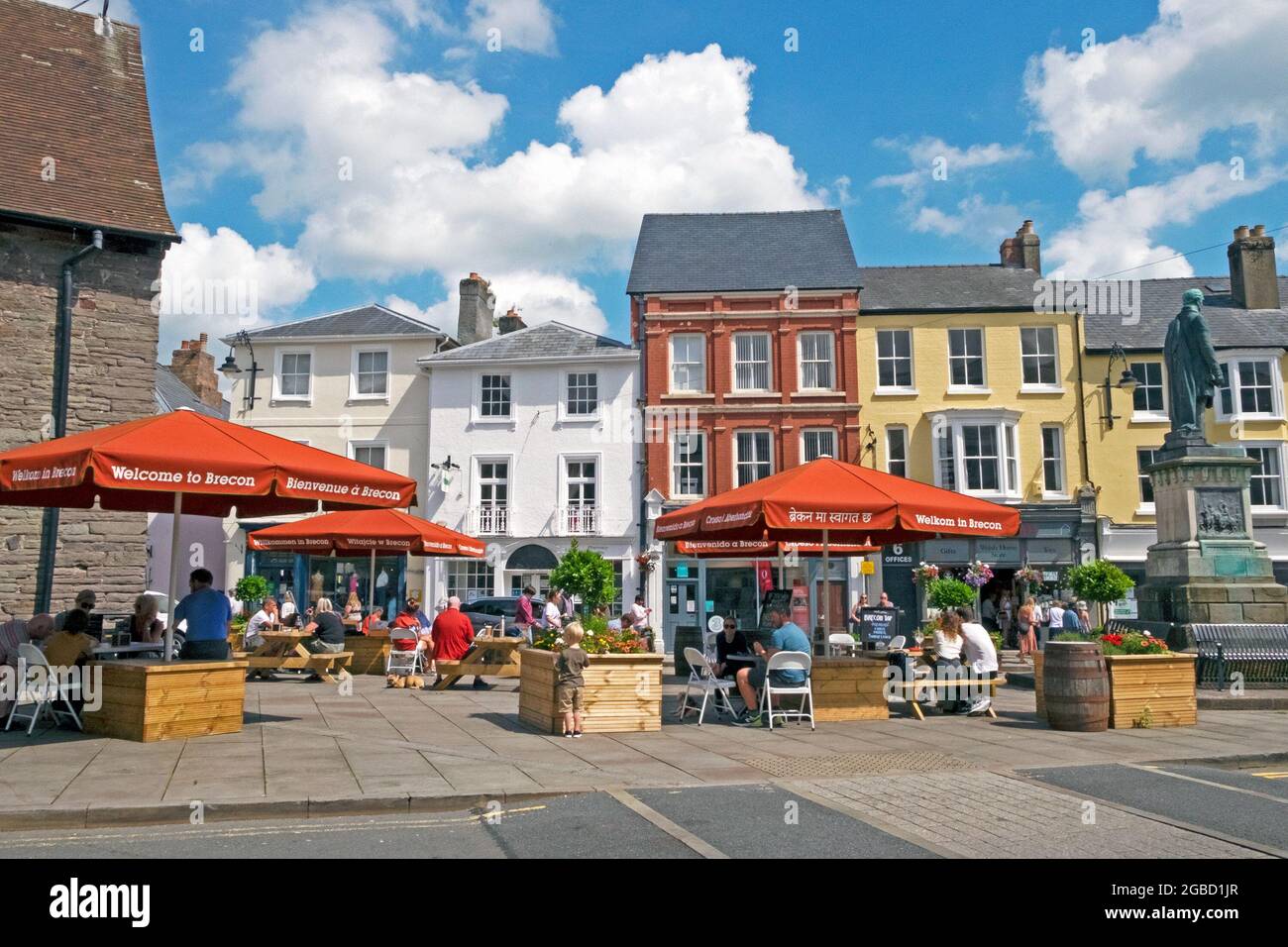 Visiteurs personnes assises sous les parasols de Brecon de bienvenue aux tables de pique-nique à l'extérieur de l'église St Marys dans le centre-ville été 2021 Powys Wales UK KATHY DEWITT Banque D'Images