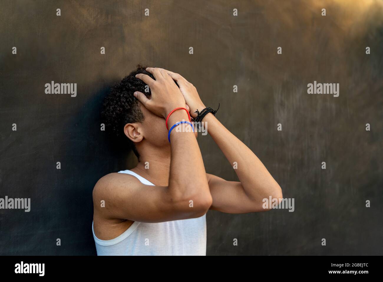 Afro latin garçon adolescent contre un mur qui embrase sa tête Banque D'Images