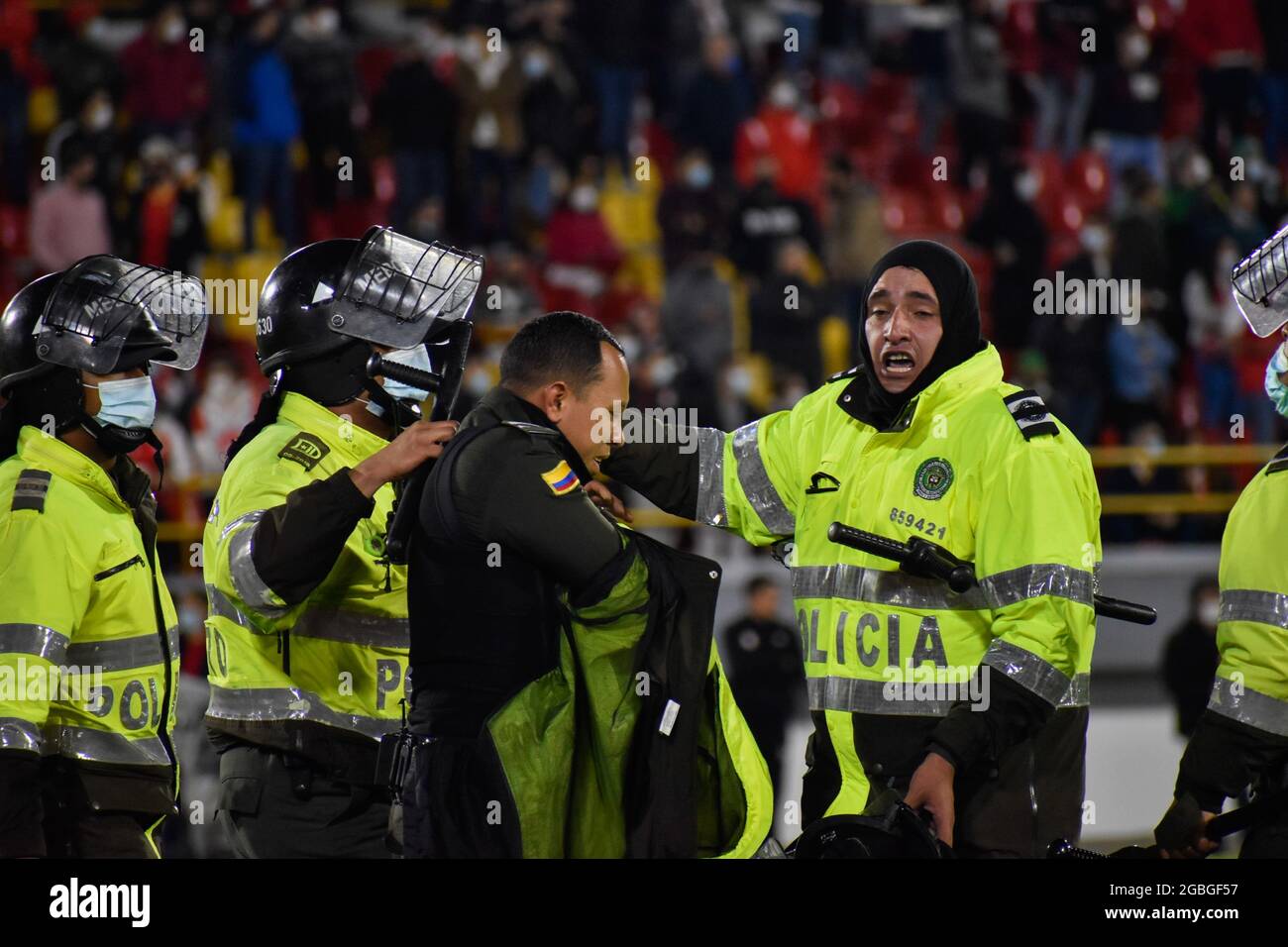 Un policier blessé lors d'affrontements est dédaigné par d'autres policiers à l'extérieur du terrain alors que les partisans de l'Independiente Santa Fe inondent le champ du stade Nemesio Camacho el Campin après que les partisans de l'équipe Atletico Nacional ont violemment attaqué les partisans de Santa Fe dans une tribune causant la suspension du Premier match de football avec des fans à Bogota, Colombie, le 3 août 2021. Banque D'Images