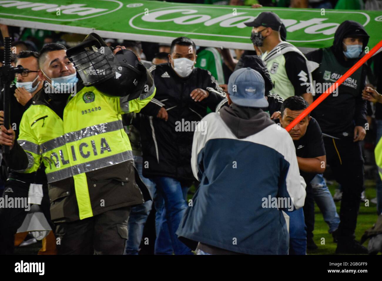 Un partisan de l'Atletico Nacional tente de nuire à un policier comme les partisans de l'Independiente Santa Fe inondent le champ du stade Nemesio Camacho el Campin après que les partisans de l'équipe Atletico Nacional ont violemment attaqué les partisans de Santa Fe dans une Tribune provoquant la suspension du premier match de football avec Fans dus aux affrontements à Bogota, Colombie, le 3 août 2021. Banque D'Images