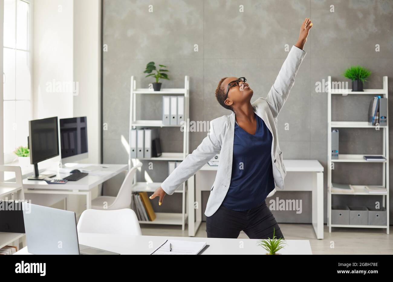 Une jeune femme d'affaires afro-américaine heureuse dansant au bureau Banque D'Images