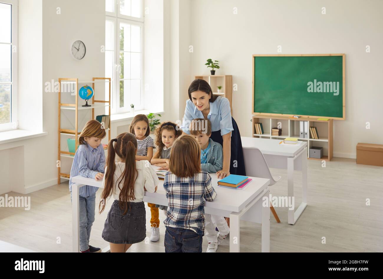 Femme amicale caucasienne enseignant amusant d'enseigner une leçon aux enfants à l'école primaire. Banque D'Images