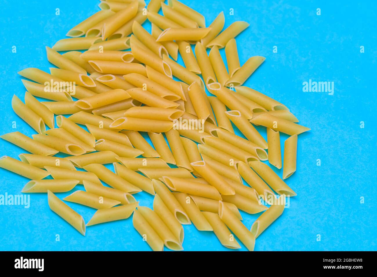 une poignée de macaroni non cuits sur fond bleu. concept de nourriture, cuisine et mode de vie sain Banque D'Images