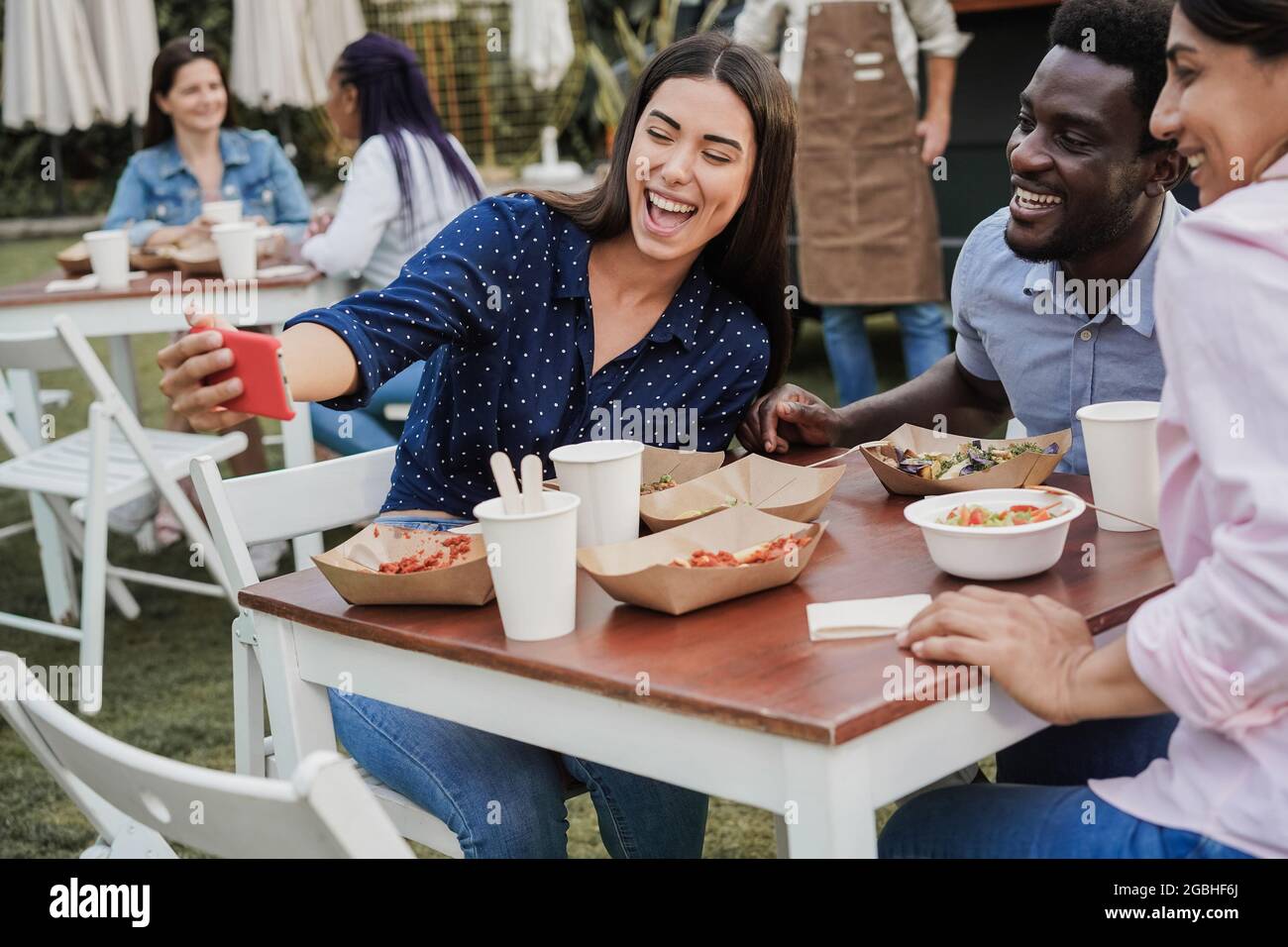 Les gens multiraciaux s'amusent à faire du selfie avec un téléphone mobile dans un restaurant de food truck extérieur - Focus sur le visage de l'homme afro-américain Banque D'Images