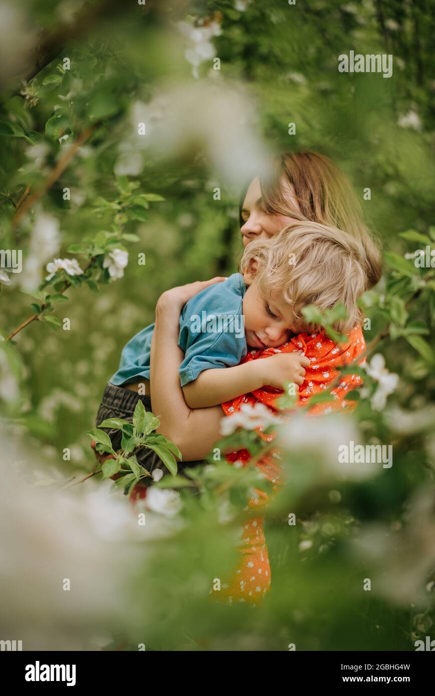 Belle scène touchante de maman et de jeune fils dans le jardin de printemps  en fleur. Bonne mère et bébé garçon embrassant. Famille, amour, concept  d'enfance Photo Stock - Alamy