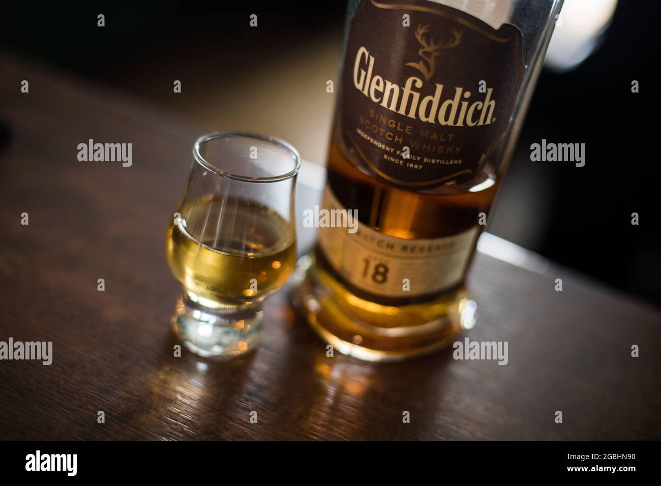Bucarest, Roumanie - 5 août 2021 : illustration éditoriale d'une bouteille de whisky scotch Glenfiddich single malt à côté d'un verre sur comptoir dans une pu Banque D'Images
