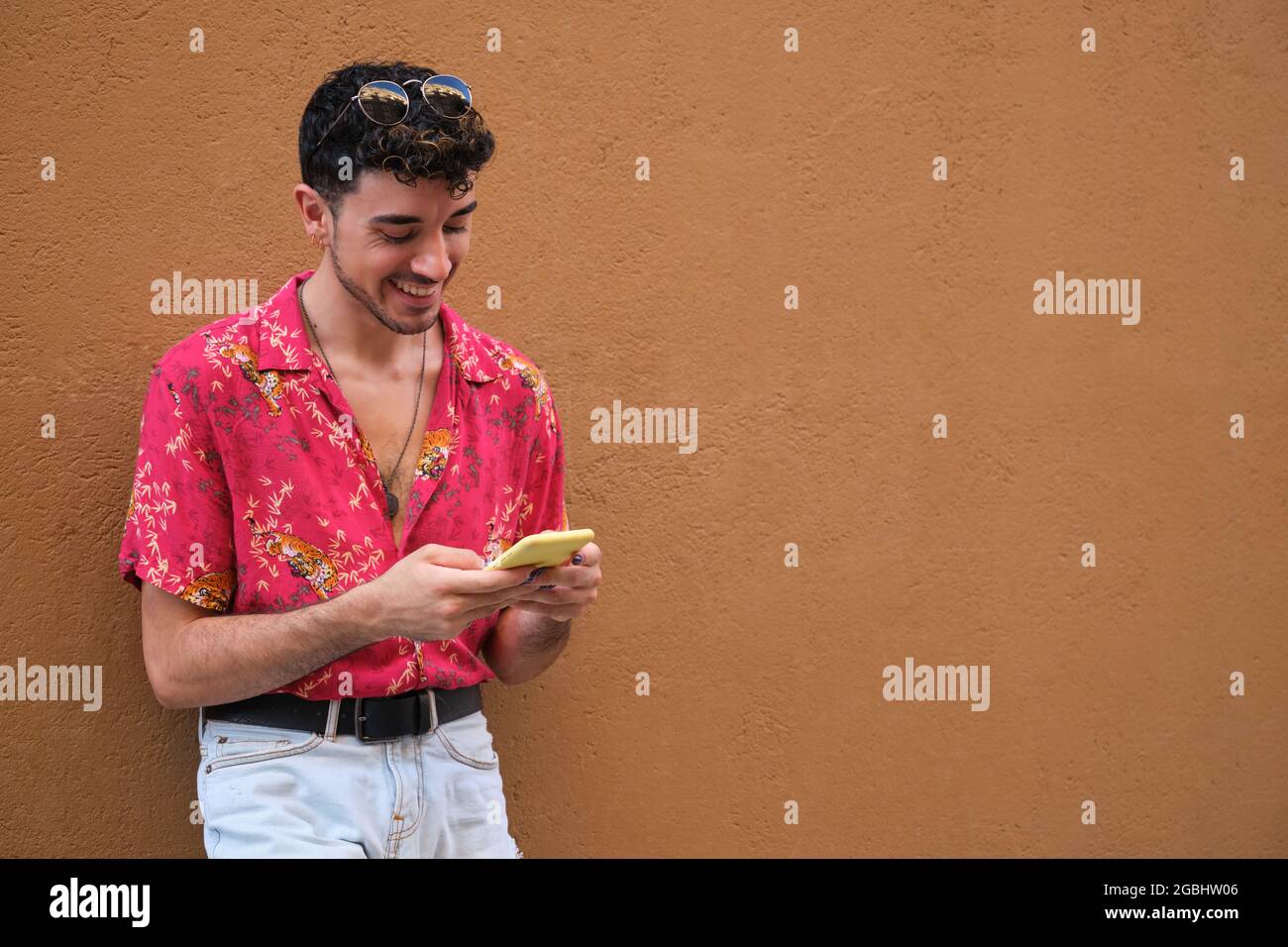 Jeune homme caucasien avec de longs ongles faux souriant et bavardant au téléphone. Banque D'Images