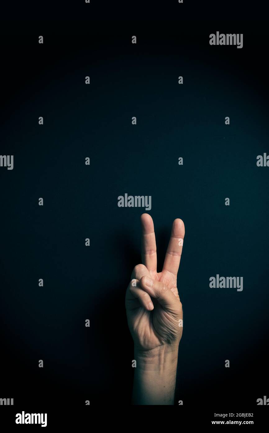 Image couleur dramatique de la main masculine démontrant l'ASL American Sign Language lettre V avec espace de copie vide pour les éditeurs Banque D'Images
