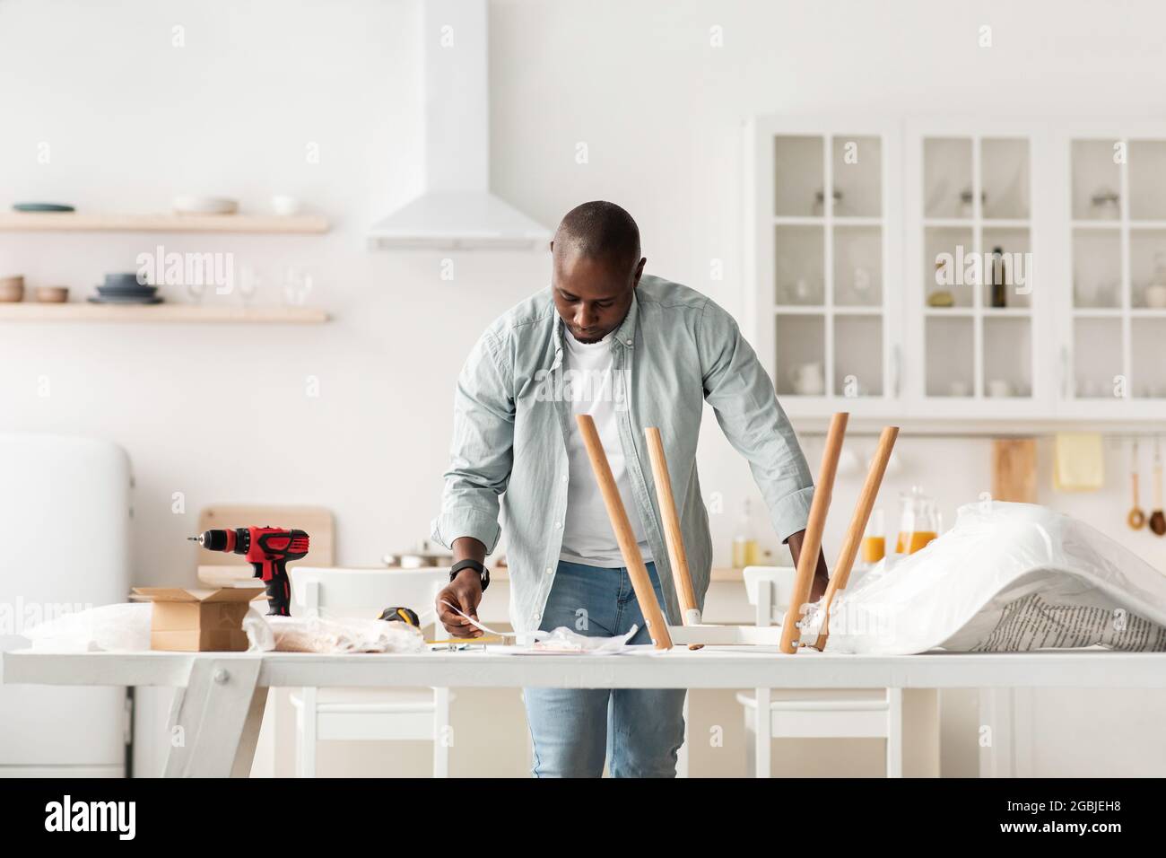 Assemblage de nouveaux meubles à la maison par vous-même. Instructions de lecture de l'homme noir millénaire concentré, intérieur de la cuisine Banque D'Images