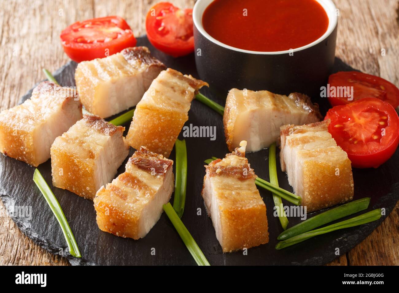 Le lechon Kawali est un plat de porc philippin populaire frite à la perfection dorée avec une sauce trempée dans le plat d'ardoise sur la table. Horizontale Banque D'Images