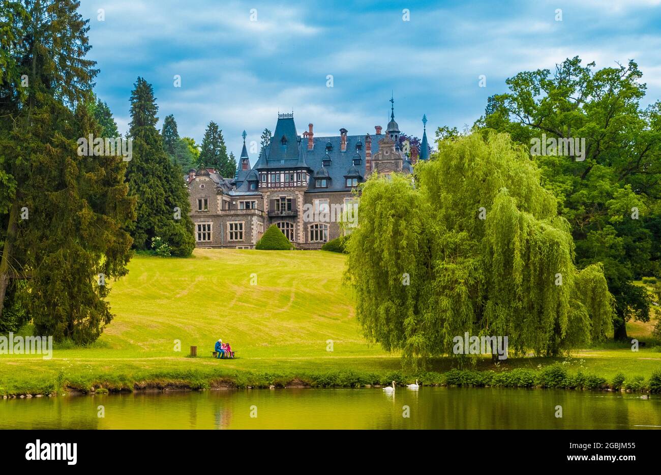 Vue pittoresque de la partie nord-est du Schlosspark Rauischholzhausen avec le château en arrière-plan. En face se trouve un étang avec deux cygnes... Banque D'Images