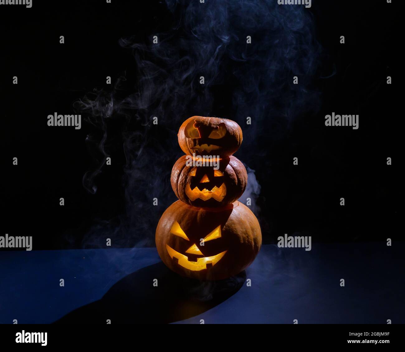 Une pyramide effrayante de Jack-o-lanterne dans l'obscurité. Un sourire éclatant et effrayant sculpté dans une citrouille. Décorations d'halloween traditionnelles. Carte de vœux horizontale Banque D'Images