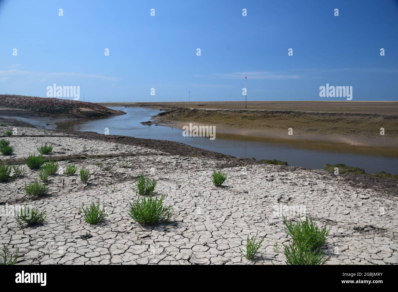 La marée est sur la rive de l'estuaire de Mersey montrant des bancs de sable exposés, des oiseaux de mer, un affluent de la rivière Alt sous le ciel bleu et la lumière du soleil d'été. Banque D'Images