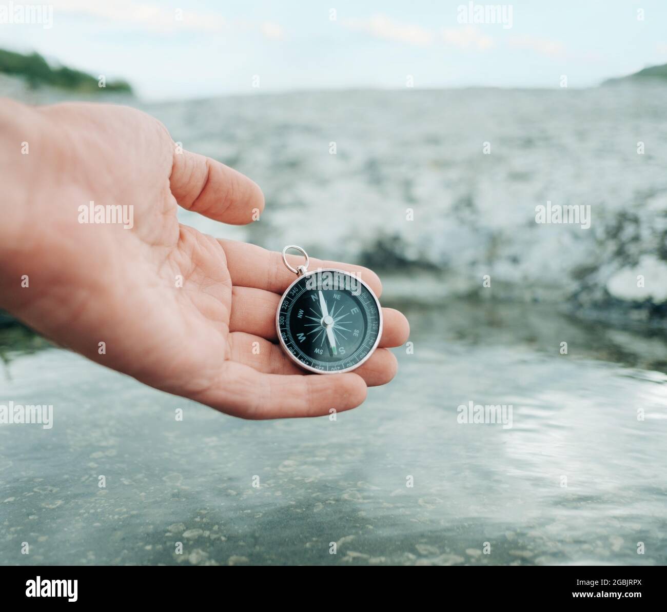 L'homme tient une boussole près de la rive de la rivière. Banque D'Images