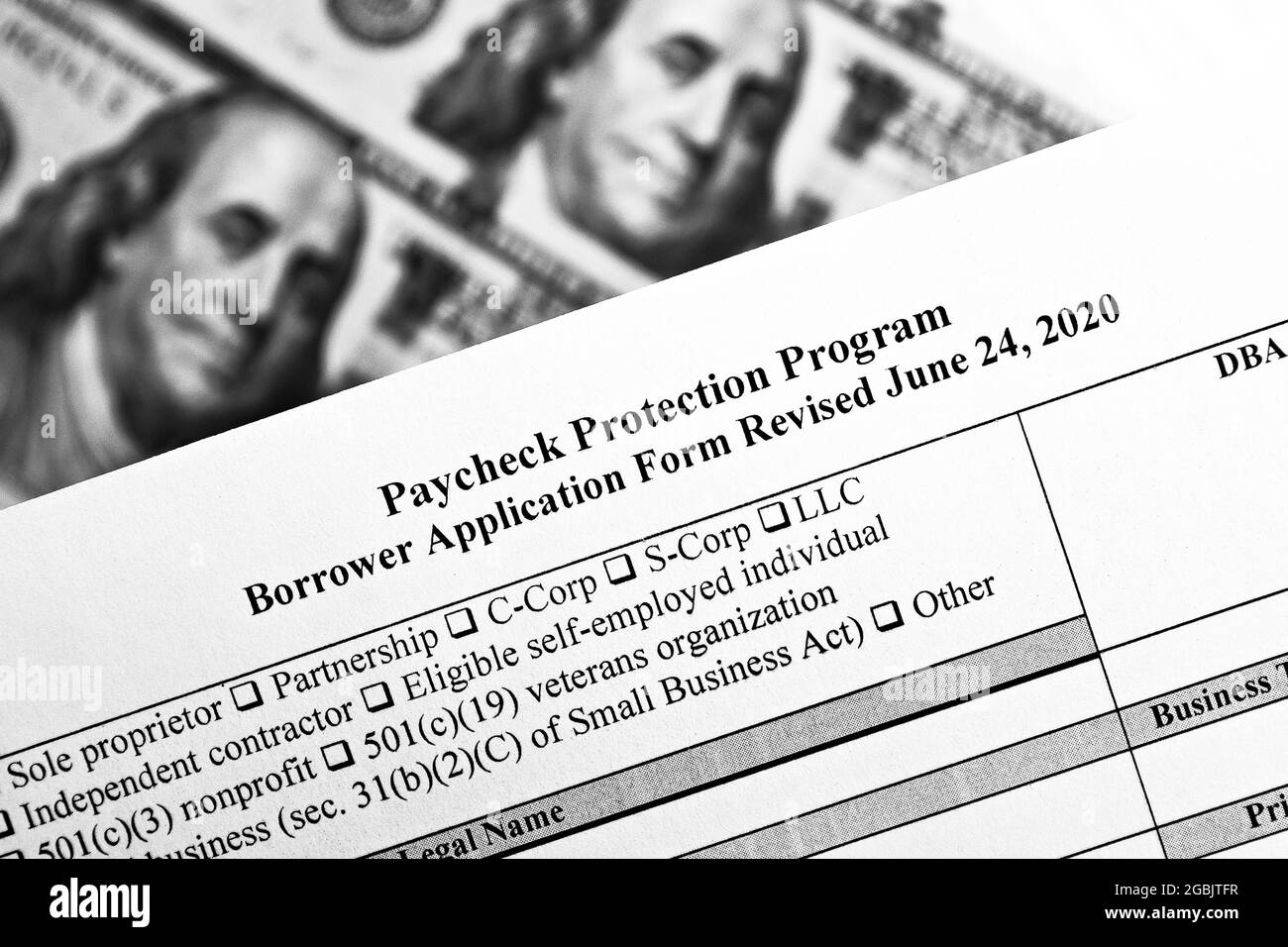 photo monochrome sélective du formulaire de demande d'emprunteur du programme de protection des chèques de paie révisé, sur fond de factures en dollars Banque D'Images