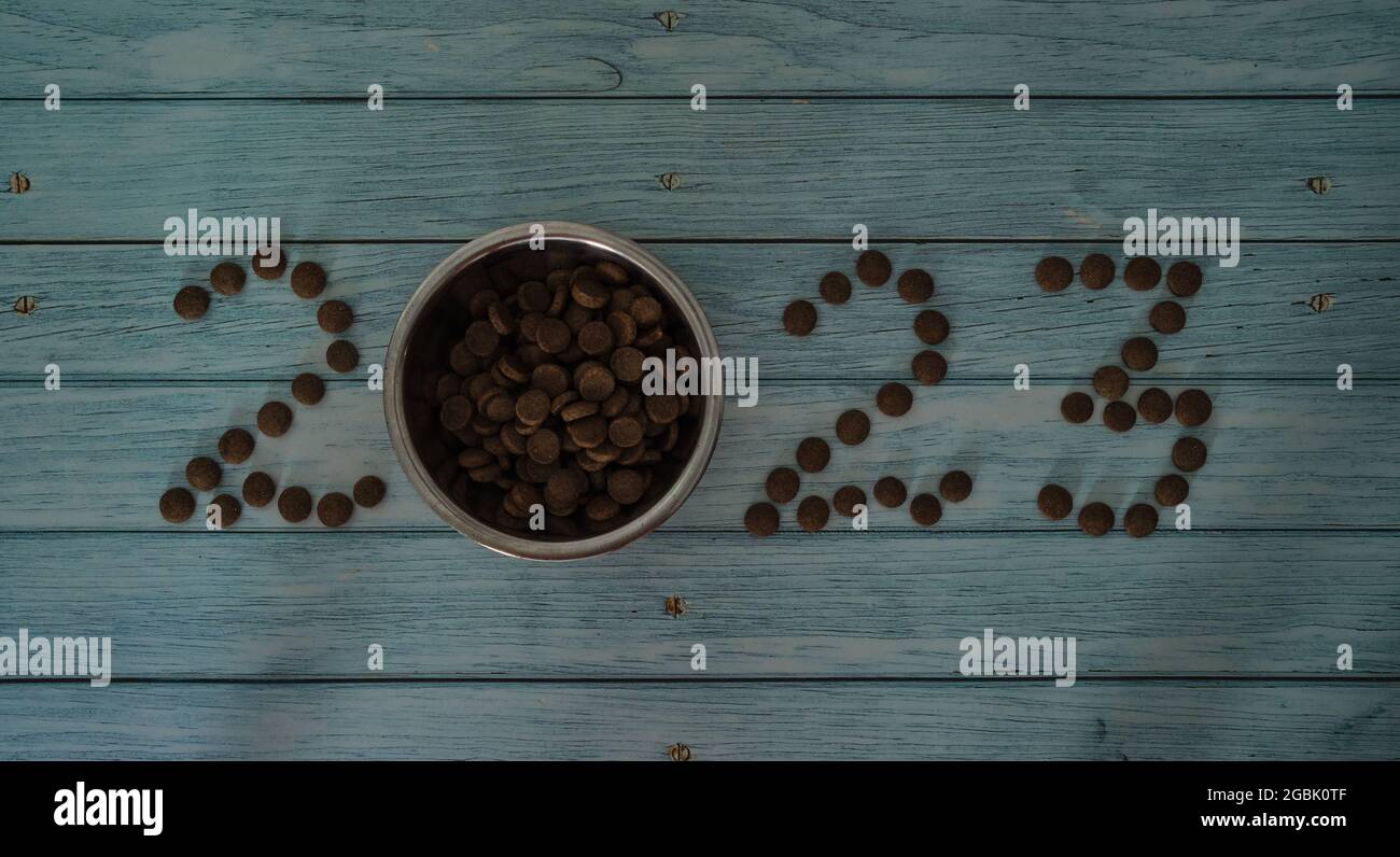 Nouveau an ou concept de Noël fond minimaliste avec les numéros 2023 de nourriture de chat ou de chien. Publicité créative d'un magasin d'animaux de compagnie. Languette en bois bleu Banque D'Images