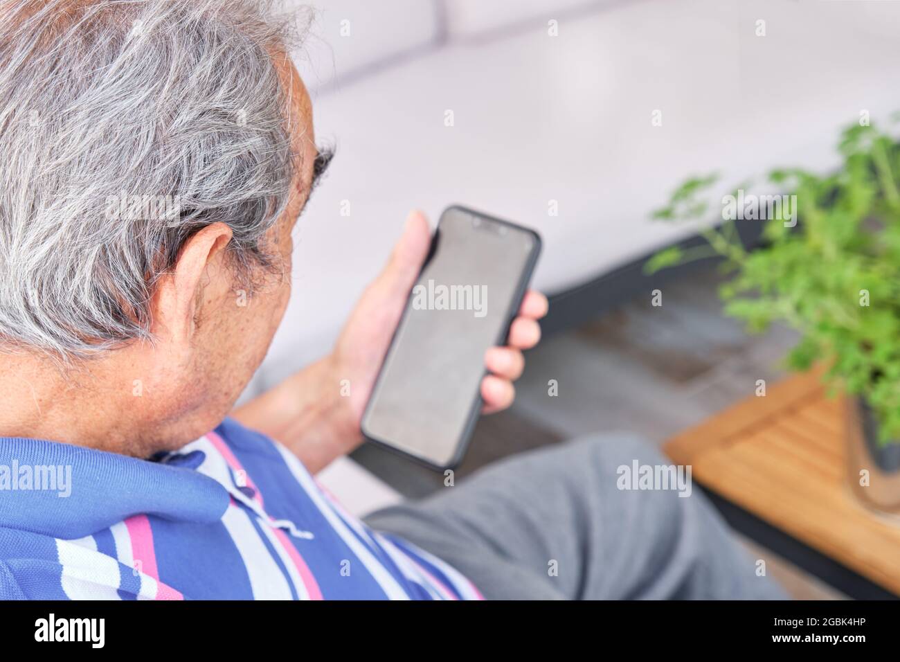 un homme plus âgé assis à l'arrière tenant un smartphone Banque D'Images