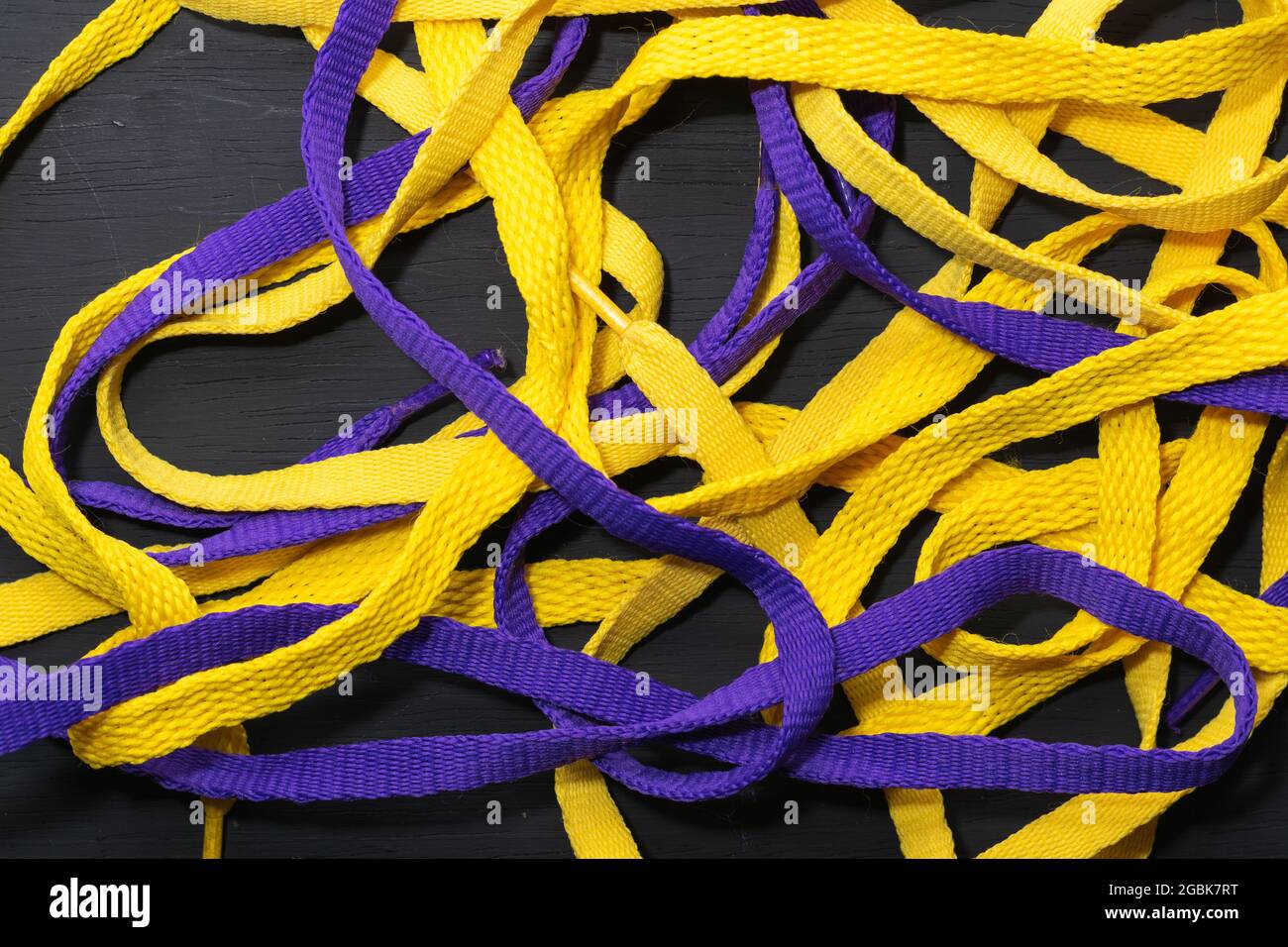 Lacets jaunes et violets, drapeau Lakers, soigneusement placé sur fond en bois noir, laissant de l'espace pour le texte publicitaire Banque D'Images