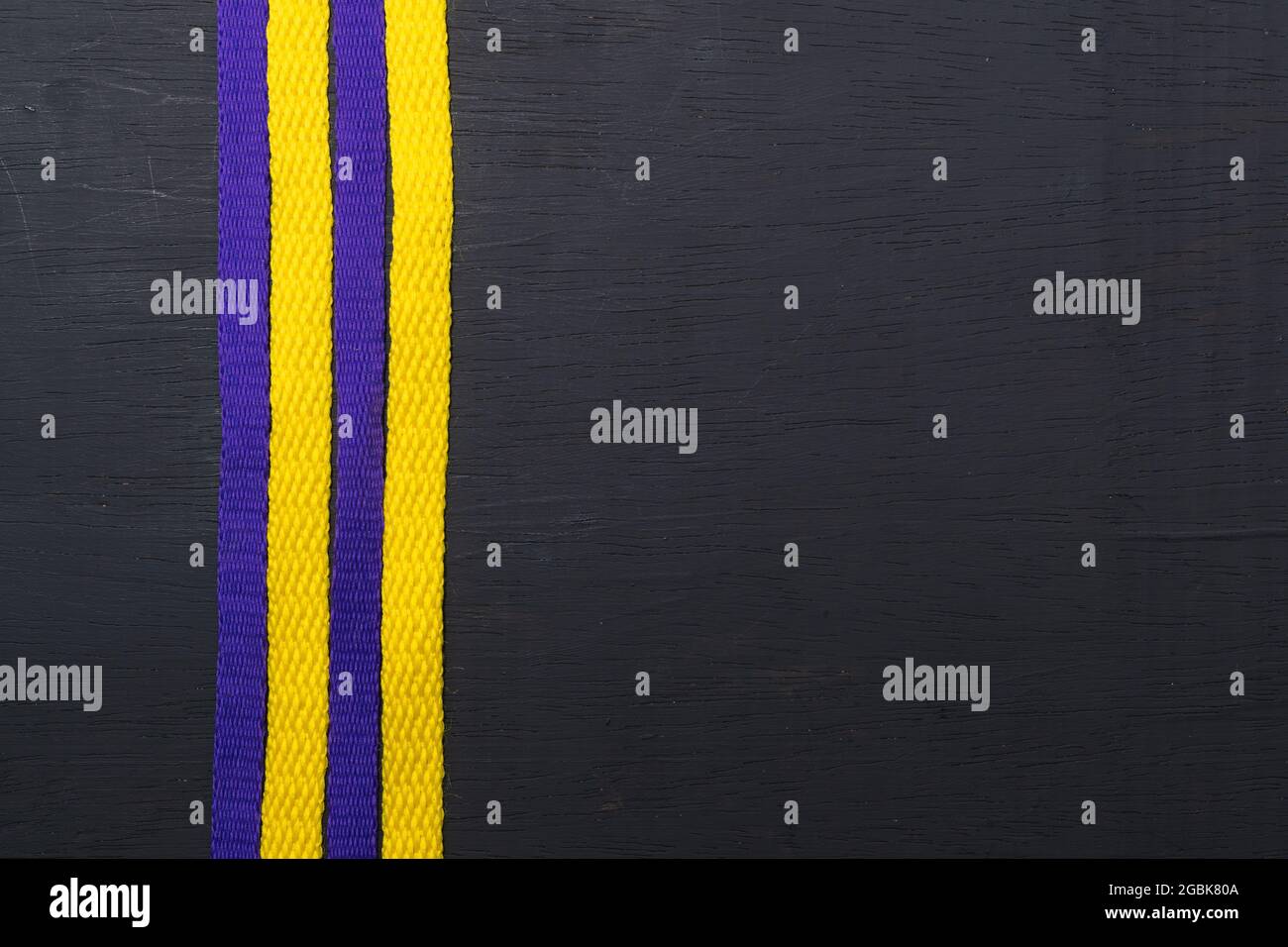 lacets jaunes et violets, drapeau lakers, sur fond noir en bois, laissant de l'espace pour le texte publicitaire Banque D'Images