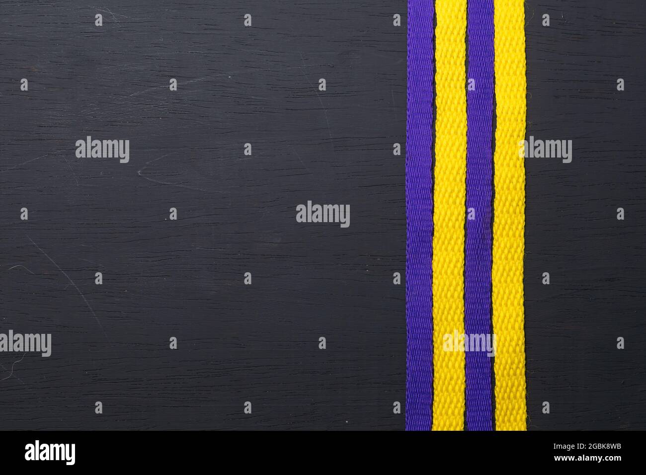 lacets jaunes et violets, drapeau lakers, sur fond noir en bois, laissant de l'espace pour le texte publicitaire Banque D'Images