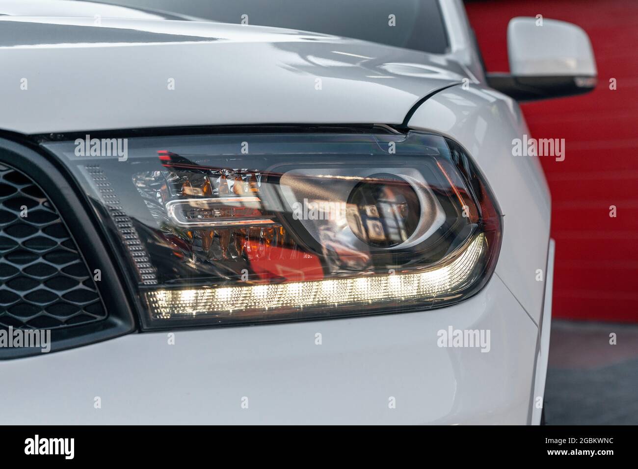 Ukraine, Odessa juillet 8 - 2021: Blanc Dodge Durango - phares avant éclairés. Gros plan sur l'un des phares à LED avec une lumière blanche Banque D'Images
