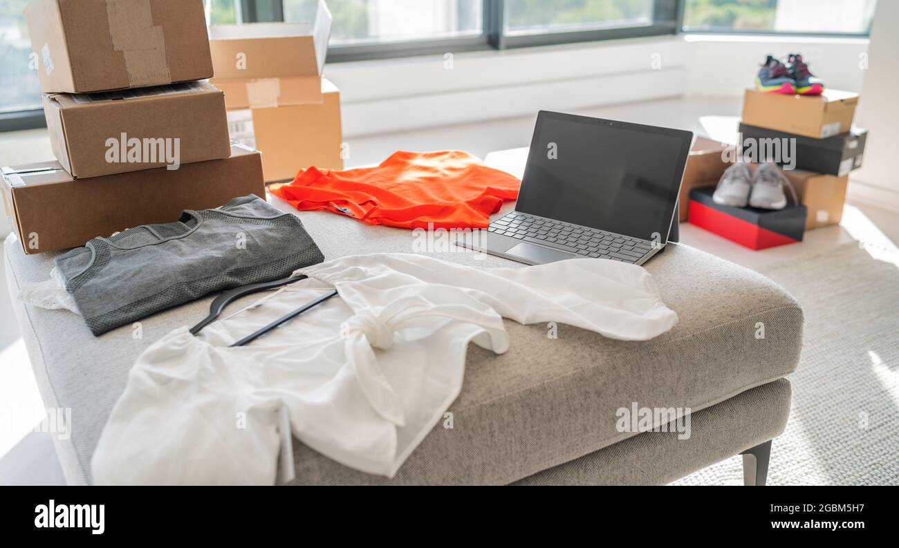 Boutique en ligne vendant de nouveaux vêtements de la maison. Petite entreprise travaillant sur l'achat d'un ordinateur portable pour les vêtements de mode expédiés dans des boîtes de carton d'expédition Banque D'Images