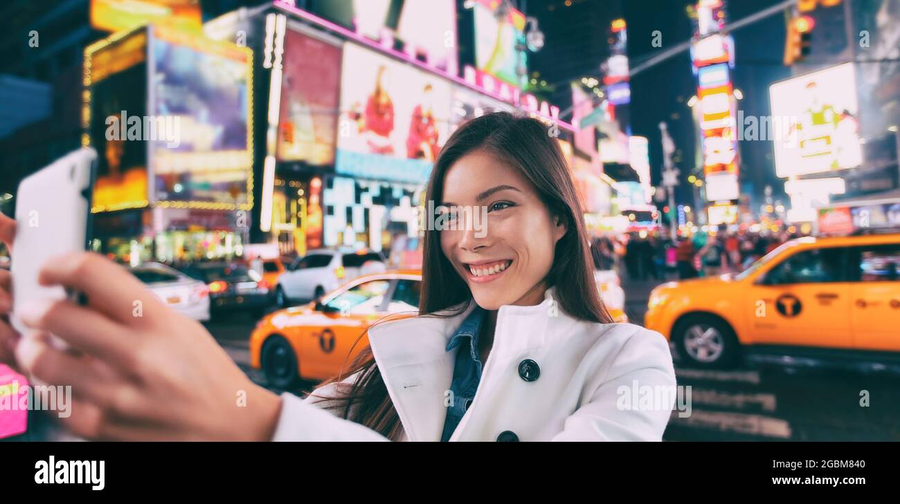 New York ville touristique selfie asiatique Happy Woman prendre des photos la nuit à Times Square, Manhattan, Etats-Unis. Fille voyageur joyeuse et souriante. Multiethnique dans Banque D'Images