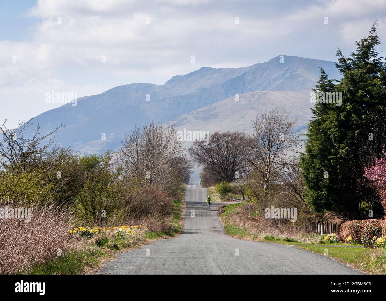 Les cyclistes passent sur une route romaine droite à travers le Lake District d'Angleterre, avec la montagne Blencathra derrière. Banque D'Images