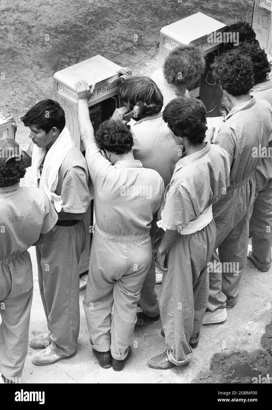 Port Isabel, Texas, États-Unis, circa1989 : les immigrants sans papiers du centre de détention du sud du Texas se réunissent autour de téléphones payants pour appeler des membres de la famille ou un avocat. ©Bob Daemmrich Banque D'Images