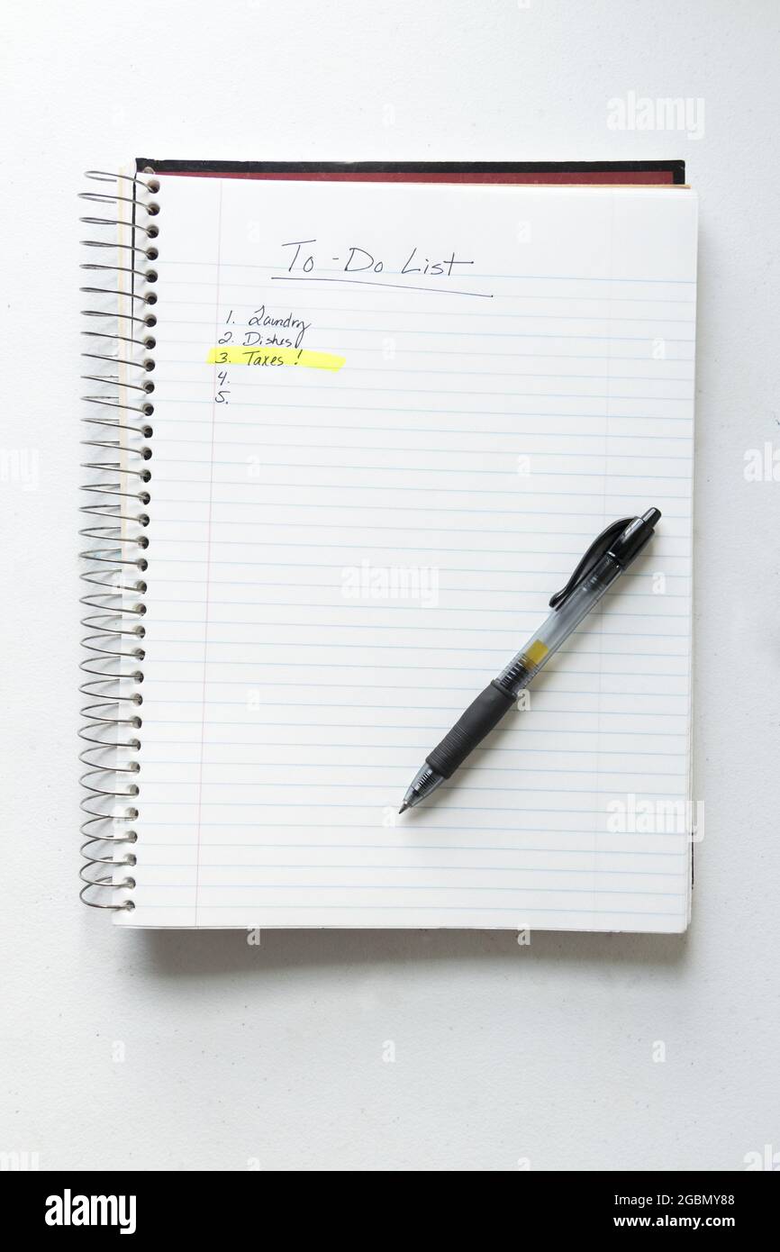 Liste complète des tâches avec taxes dans un bloc-notes en spirale avec un stylo noir Banque D'Images