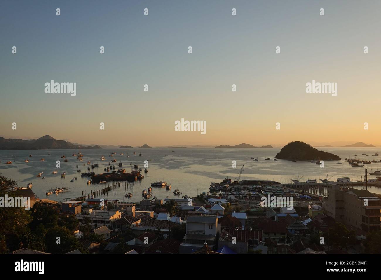 Coucher de soleil sur la ville et le port de Labuan Bajo, avec de nombreux bateaux de croisière traditionnels de Phinisi ancrés comme la ville est le point d'entrée du Komodo national Banque D'Images