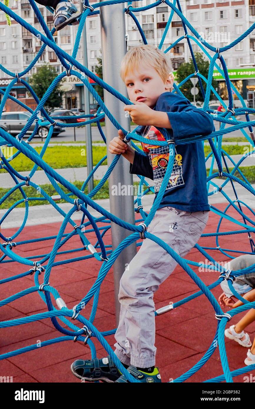 un garçon joue dans un parc de la ville sur une attraction de corde, Banque D'Images