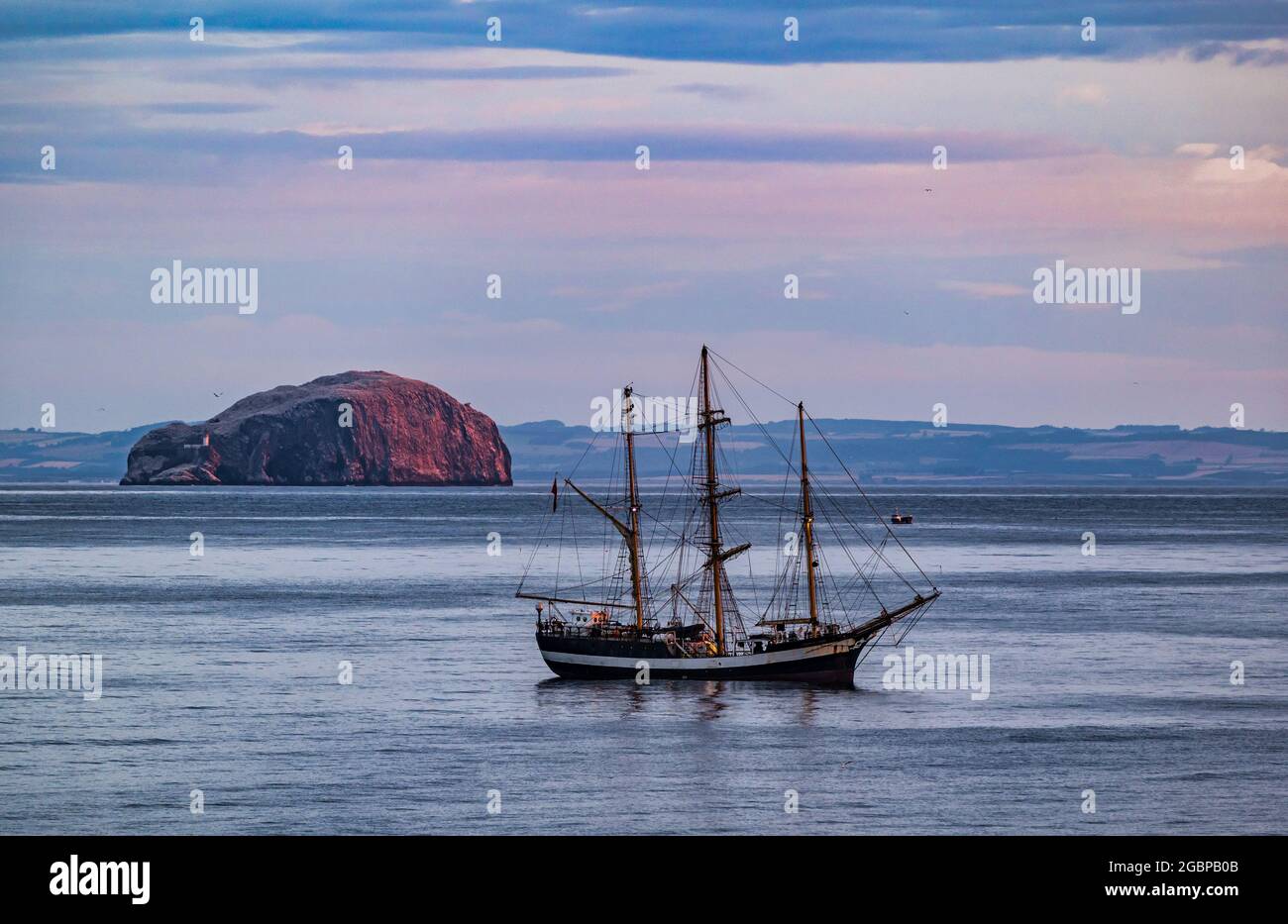 Firth of Forth, Écosse, Royaume-Uni, 5 août 2021. Lever du soleil : le grand bateau Pelican de Londres, une rigeuse carrée de classe A, est ancré au large de la côte de Dunbar avec une vue sur le Bass Rock lorsque le soleil se lève. Le navire est sur la dernière étape d'une tournée autour de la Grande-Bretagne Banque D'Images