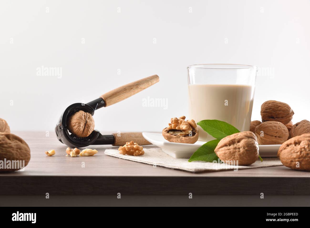 Verre plein de lait de légumes de noix avec fruits autour sur table en bois avec le fond isolé de casse-noisette Banque D'Images
