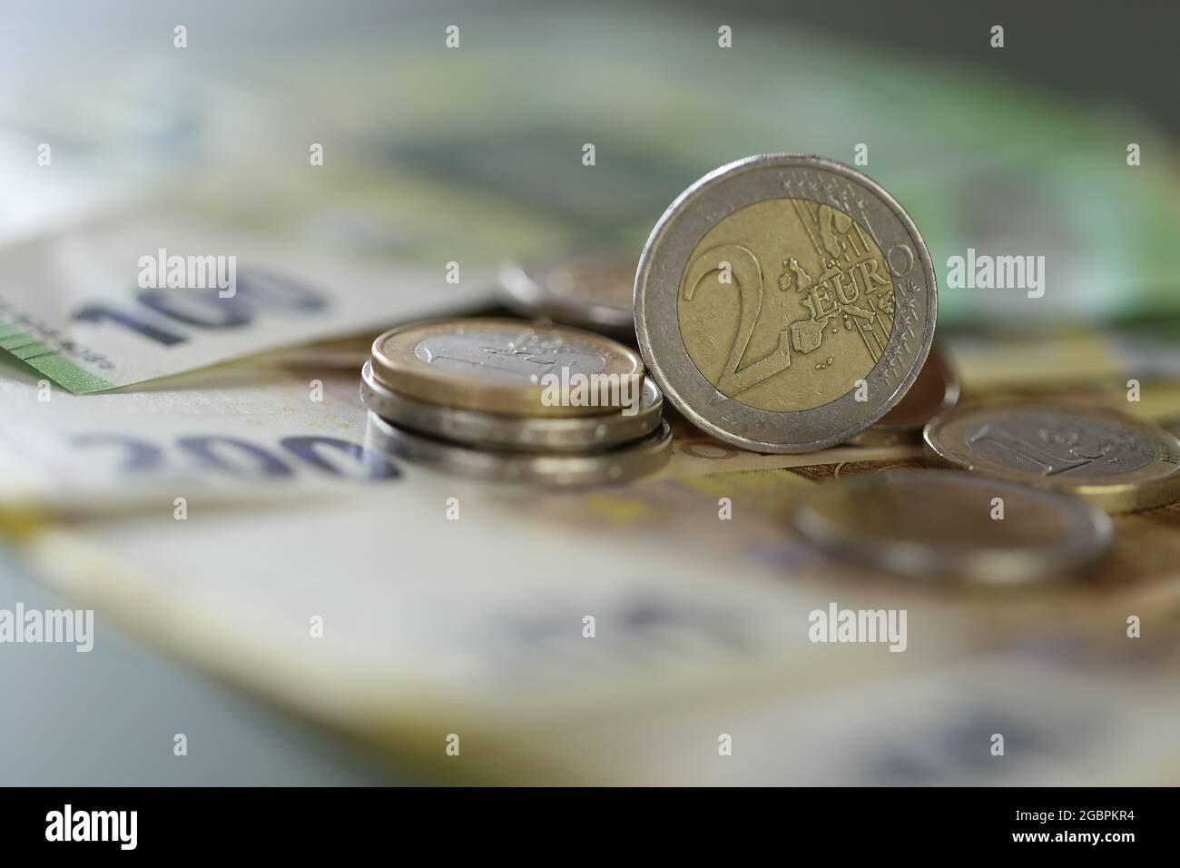 Pièces en euros et billets en euros sur fond vert. Deux pièces en euros. Monnaie européenne. Finances et épargne. Banque D'Images