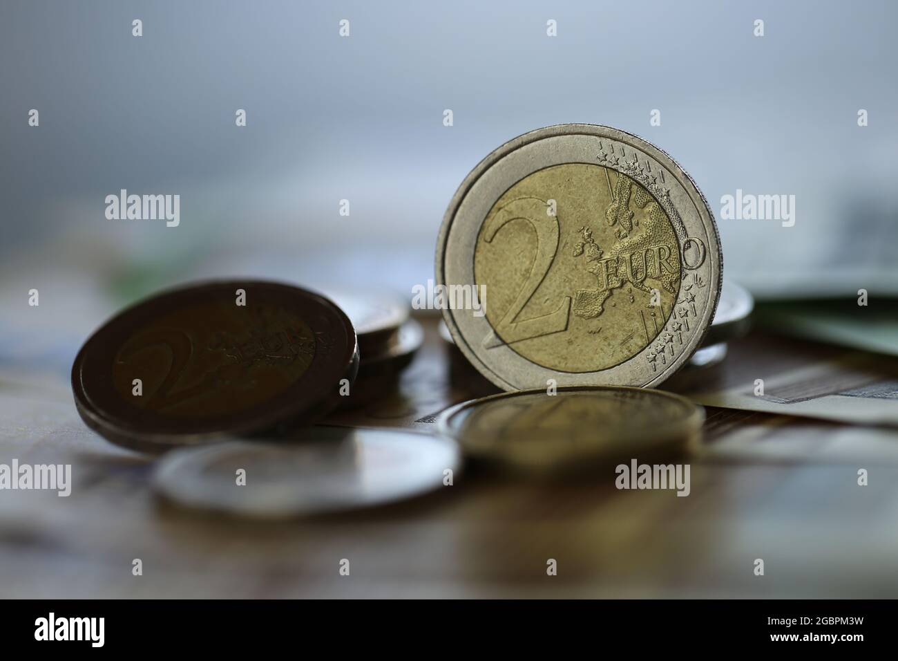 Deux pièces en euros. Pièces en euros et billets en euros sur fond vert flou. Monnaie européenne. Finances et épargne. Banque D'Images