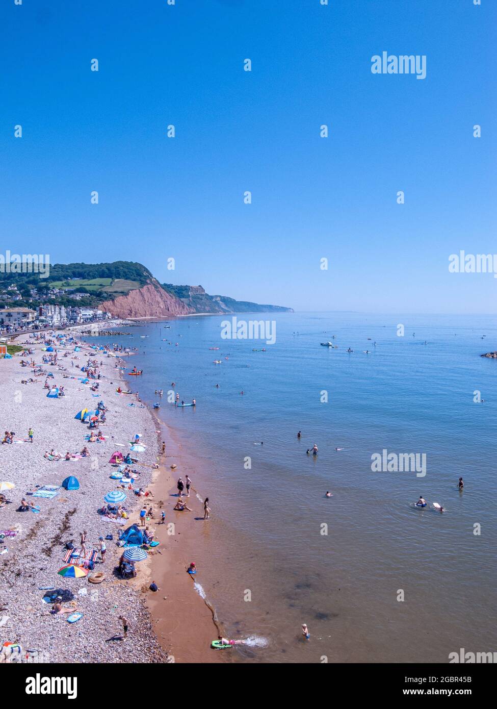 Vue panoramique sur une plage sur la côte sud de l'Angleterre lors d'une journée chaude, avec des gens qui s'amusent sur la plage et dans l'eau Banque D'Images