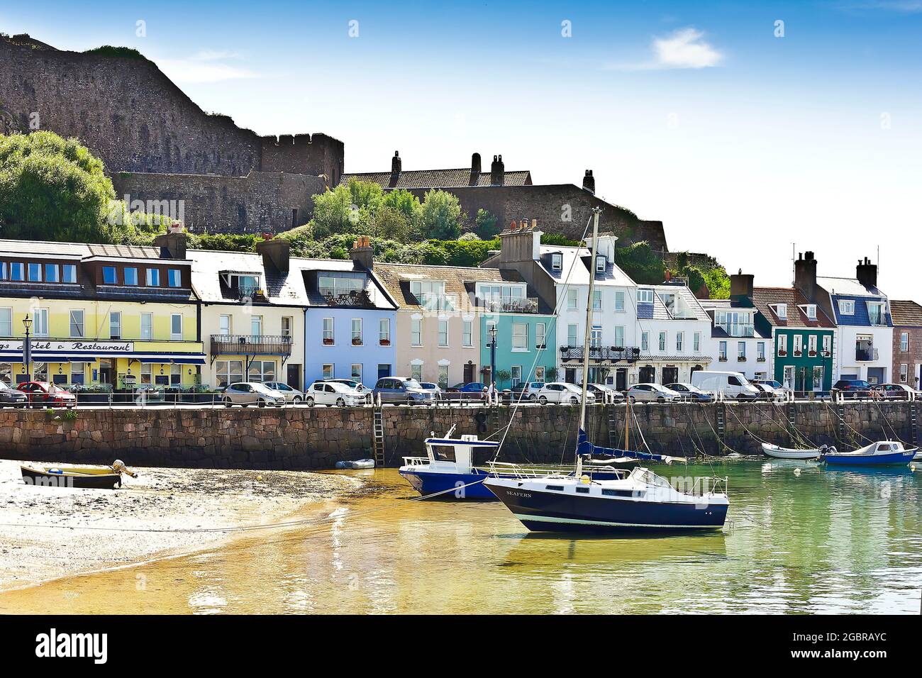 Gorey, Jersey, Îles Anglo-Normandes, GB - 7 juillet 2016 : bateaux et yachts ancrés dans le port, bâtiments de bord de mer en arrière-plan. Banque D'Images